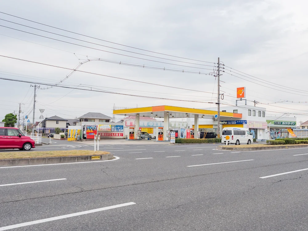 お肉バー ま、いっかへの行き方：店舗前からGSを望む