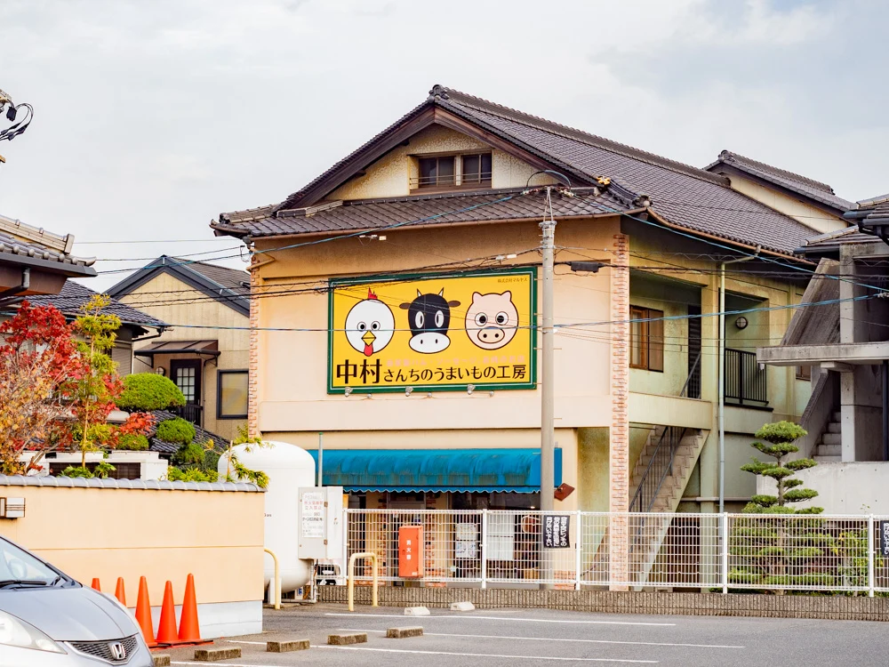 中村さんちのうまいもの工房への行き方：甲羅本店駐車場から中村さんちのうまいもの工房を見る