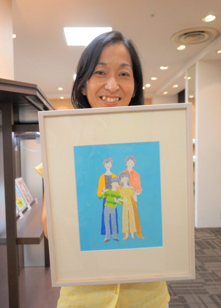 自身の家族のイラストを持ったフジワカマリさん