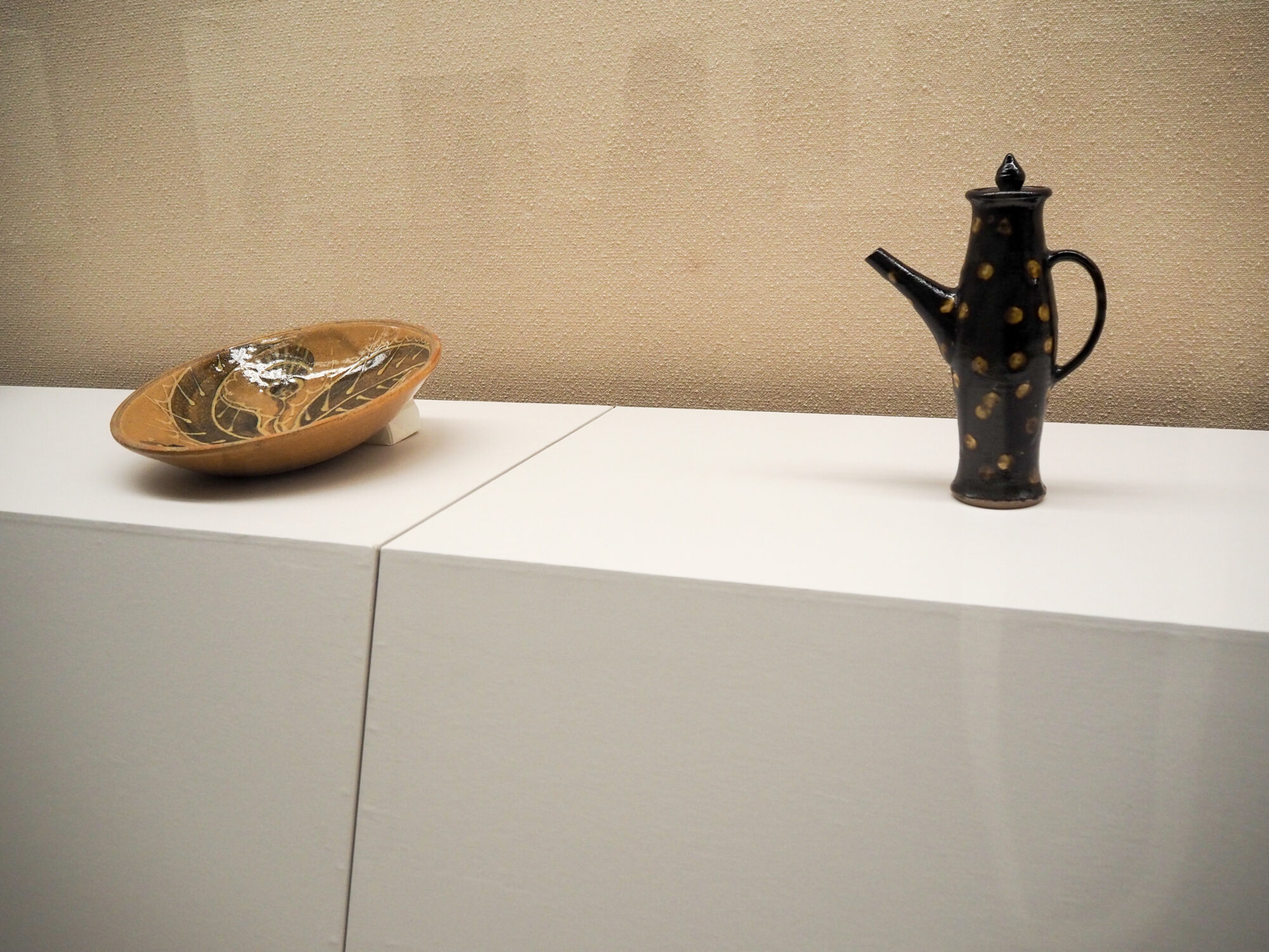 左から、小河原虎吉「飴釉地掛筒描絵皿」、小河原虎吉「黒釉抜紋注瓶」