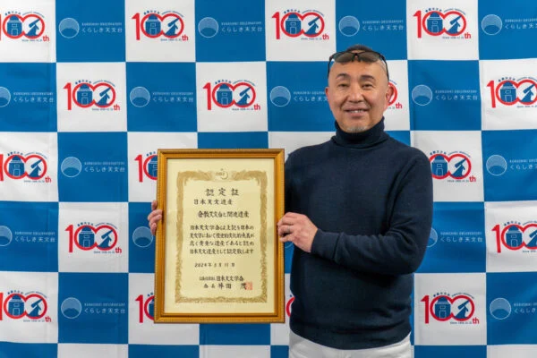 倉敷天文台100周年記念バックボードの前に立つ原館長