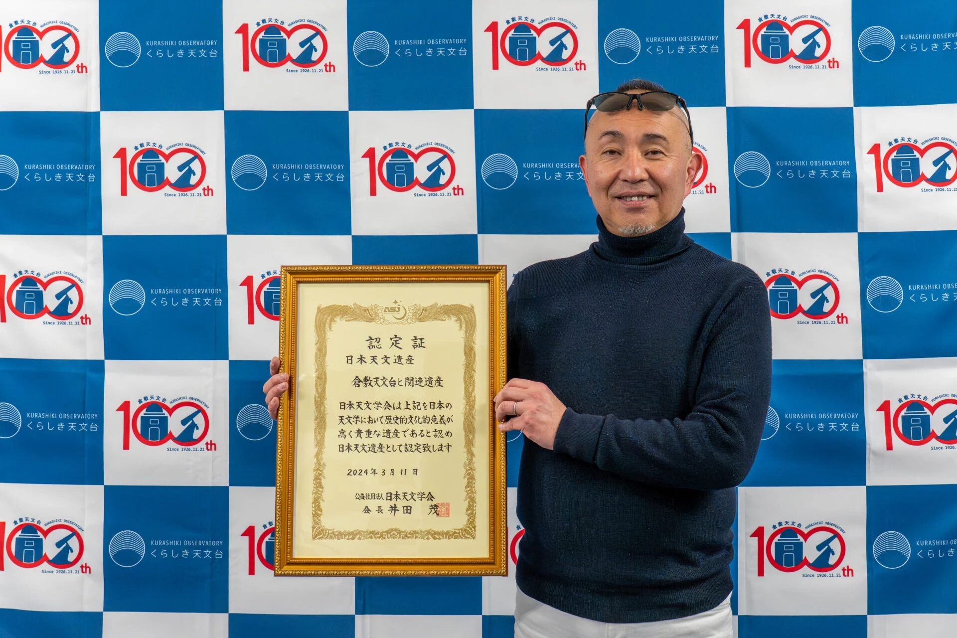 倉敷天文台100周年記念バックボードの前に立つ原館長