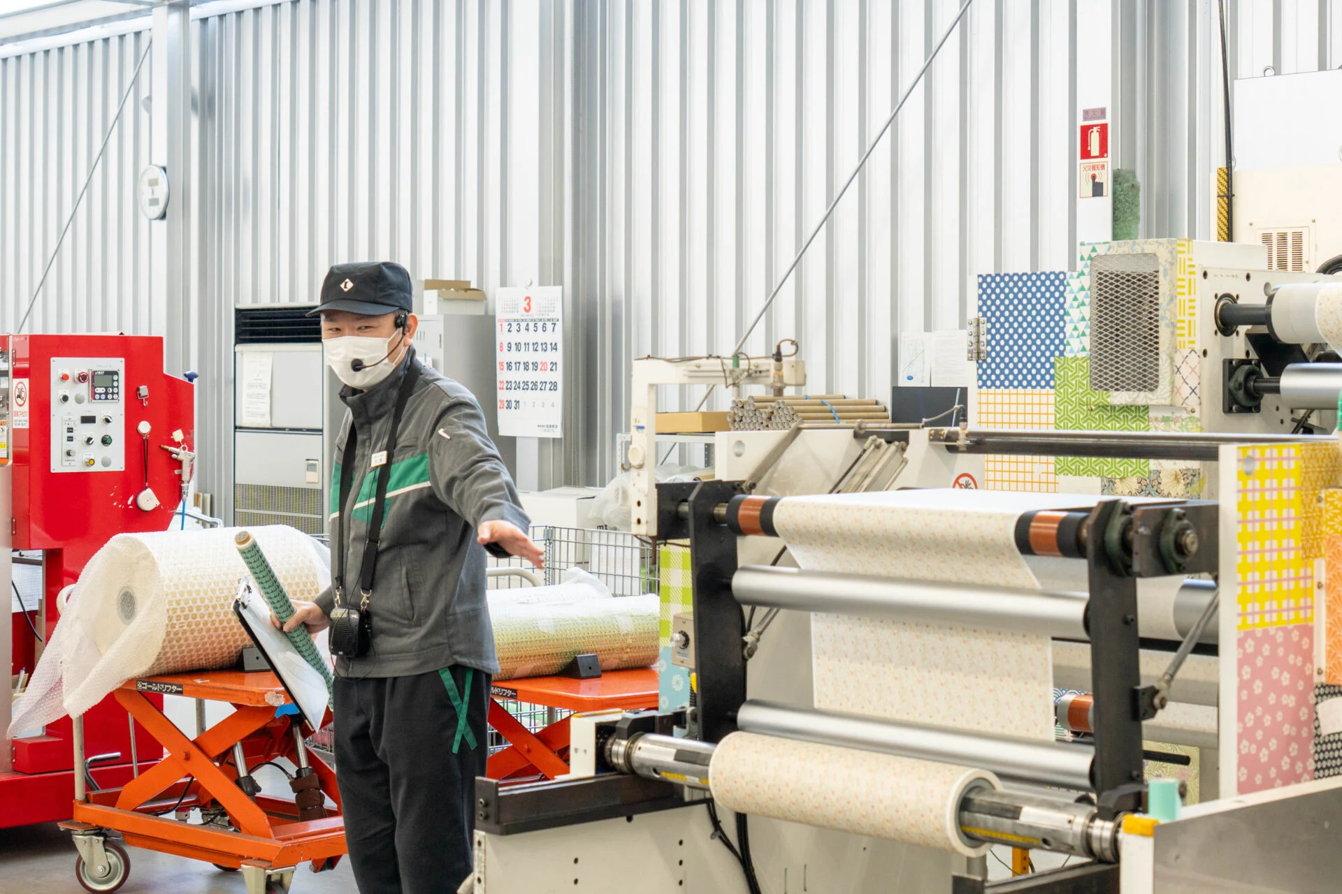 柄が印刷された大きな幅のマスキングテープを、機械を使って紙管(しかん)に巻く
