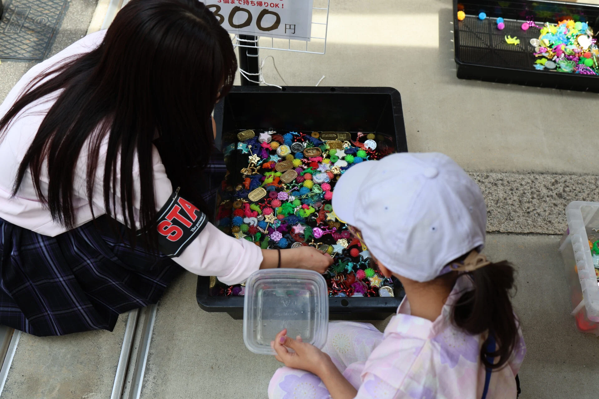 子どもにおもちゃすくいのやり方を教えている高校生