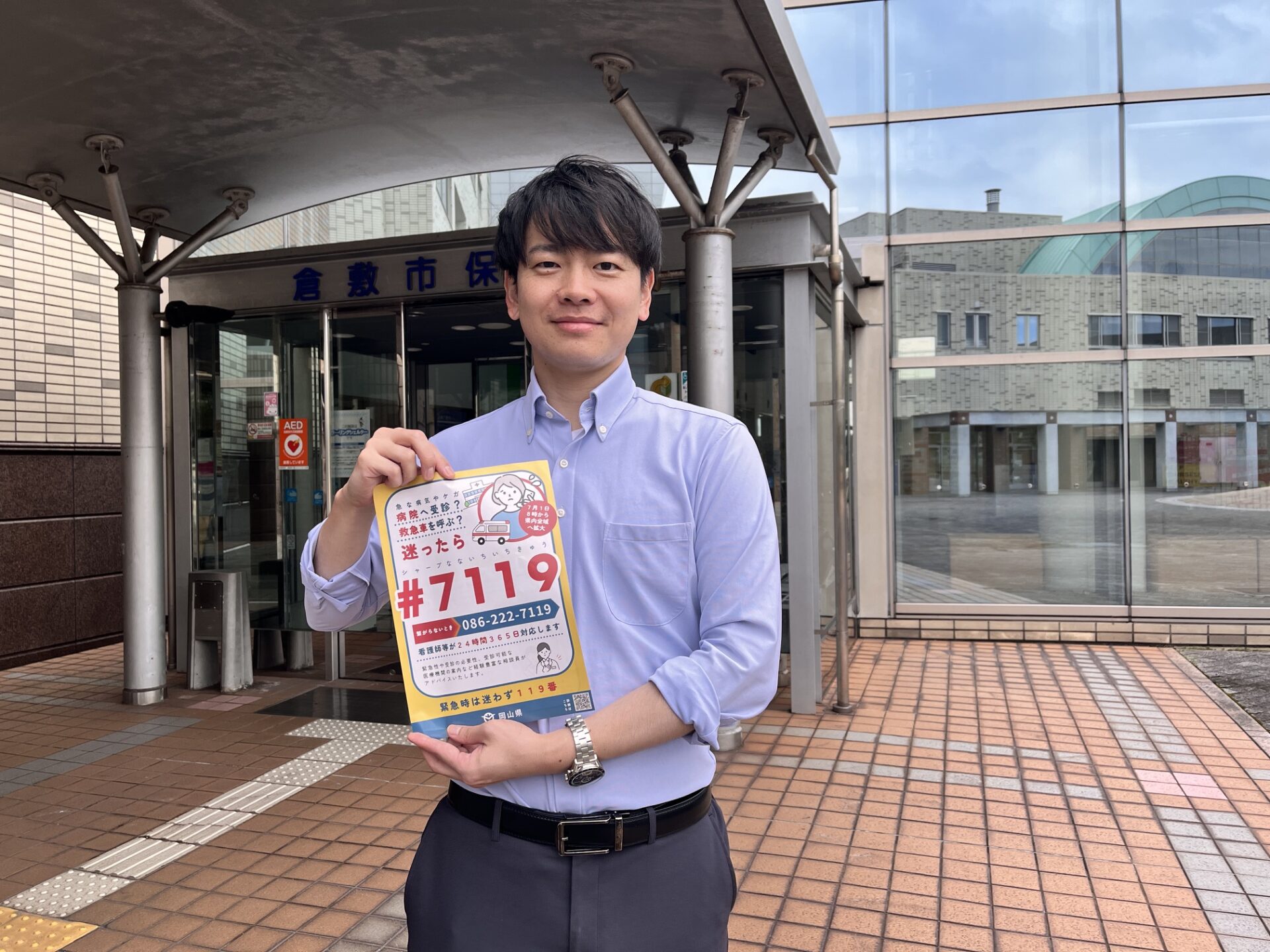 倉敷市保健所前で「#7119」のポスターを持つ担当者