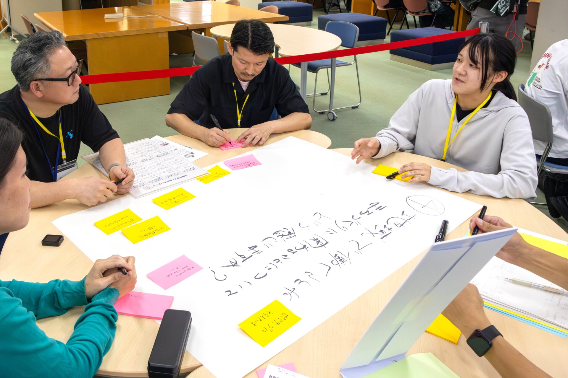 Companies and students exchanging opinions using a poster and sticky notes around a table